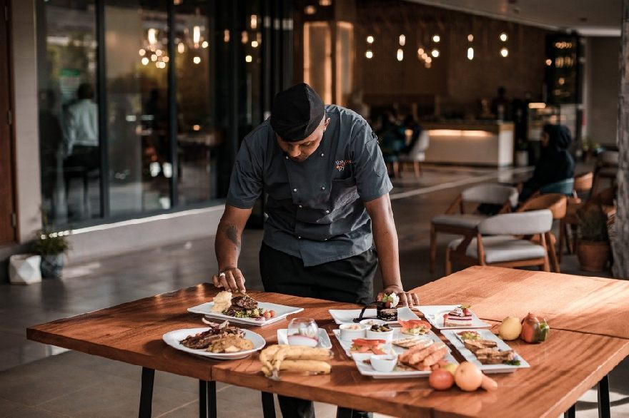 chef koch am tisch anrichten mit leckeren asiatischen speisen.